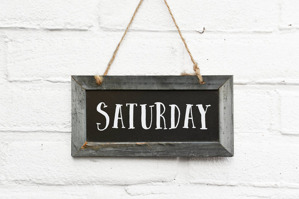 Hello saturday text on hanging board white brick outdoor wall - Photo, Image