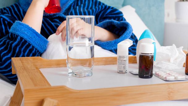 Closeup image of sick person lying in bed and using medicines - Photo, Image