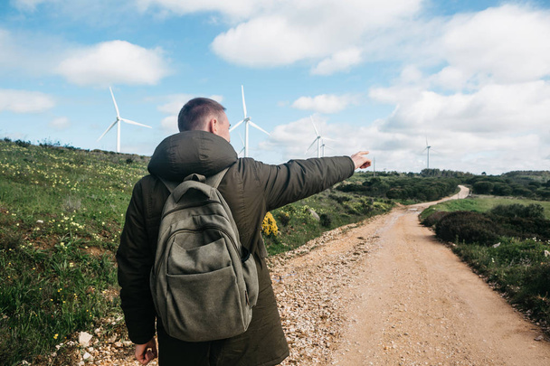 Een toerist met een rugzak naast windmolens in Portugal. - Foto, afbeelding