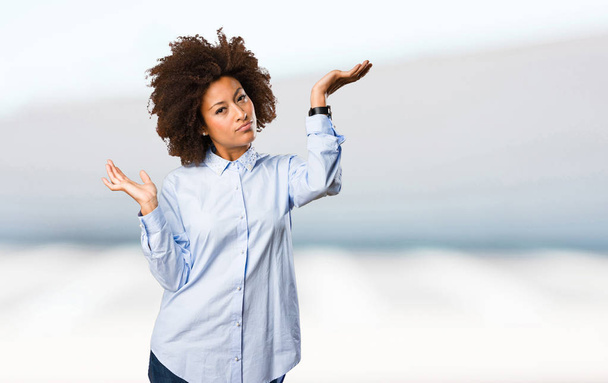 giovane donna nera in camicia blu dubitare su sfondo sfocato
 - Foto, immagini