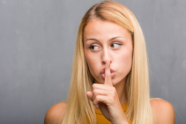 portrait of natural young blonde woman keeping secret or asking for silence - Foto, Imagen