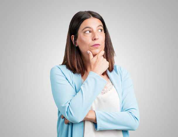 Middle aged woman doubting and confused, thinking of an idea or worried about something - Photo, Image