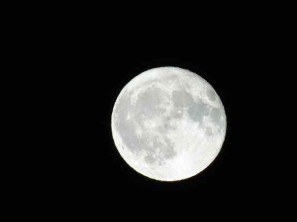 Una fotografía increíble de la luna llena bajo un cielo oscuro con algunas pequeñas estrellas en el fondo
 - Foto, imagen