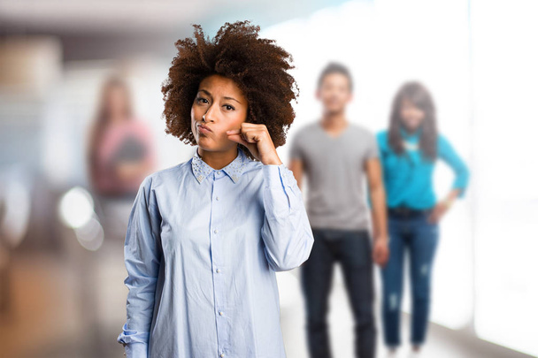 jonge zwarte vrouw doen stilte gebaar met wazig mensen op achtergrond - Foto, afbeelding