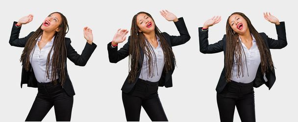 Conjunto de joven mujer negra de negocios escuchando música, bailando y divirtiéndose sobre fondo gris
 - Foto, Imagen