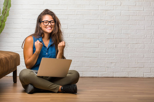 Portrait of young latin woman sitting on floor very happy and excited - Foto, Bild