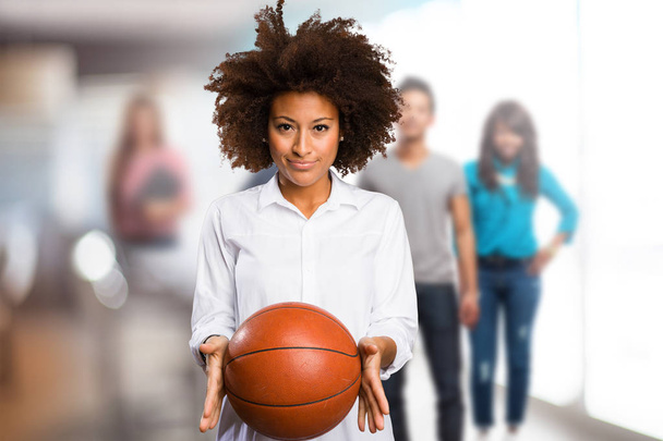 giovane donna nera che tiene in mano una palla da basket con persone sfocate sullo sfondo
 - Foto, immagini