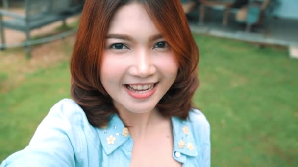 Atractiva hermosa feliz mujer asiática blogger usando smartphone para selfie y grabación haciendo comida vlog video para sus suscriptores y su canal en la cafetería y restaurante
. - Imágenes, Vídeo