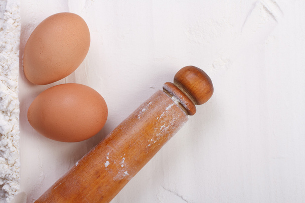 Мука и яйца ингредиенты для выпечки. Rolling pin close seup
 - Фото, изображение
