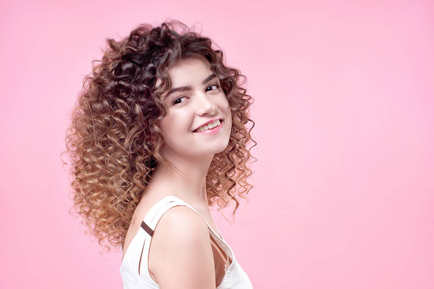Happy smiling young woman with amazing hairstyle curly shine hair in white shirt - Фото, изображение