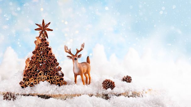 Christmas holiday concept with deer, pine cone and Christmas tree made from stock of cinnamon and anise star. - Valokuva, kuva