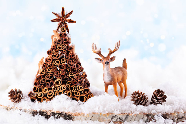 Christmas holiday concept with deer, pine cone and Christmas tree made from stock of cinnamon and anise star. - Valokuva, kuva