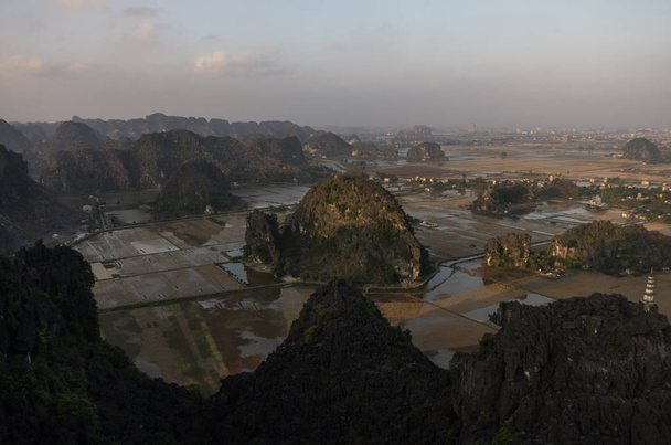 Καταπληκτική πανοραμική θέα του ρυζιού τομείς, ασβεστολιθικά πετρώματα και βουνοκορφή παγόδα από ναό Mua κολλάει στο βράδυ. Binh Ninh του Βιετνάμ. Φόντο τοπία και προορισμούς ταξιδιών - Φωτογραφία, εικόνα
