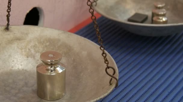 Pesos de ferro e latão adicionados em um lado de uma balança mecânica vintage enquanto pesa
 - Filmagem, Vídeo