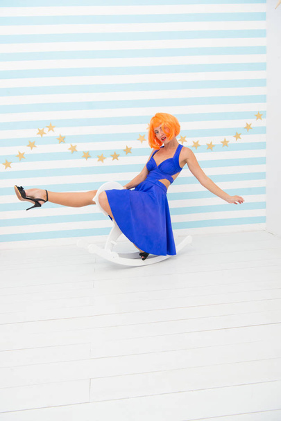 Fun and entertainment. Girl wig rides swing little horse. Feel childish. Lady red or ginger wig blue dress rides rocking horse. Comic and humorous concept. Woman playful cheerful mood having fun - Photo, Image