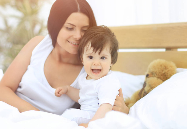 Portrait of a beautiful mother with her baby in the bedroom - Foto, Bild