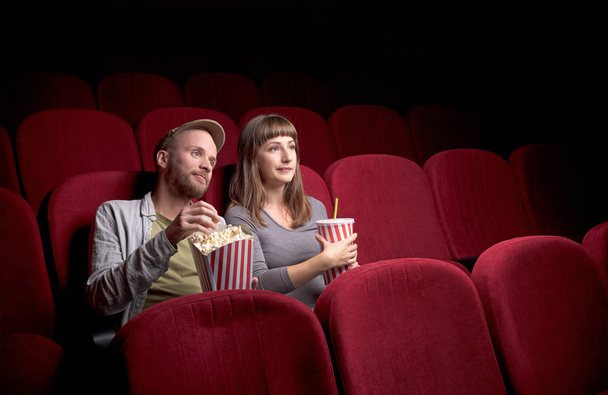 Young couple sitting at red movie theatre - Foto, Imagen