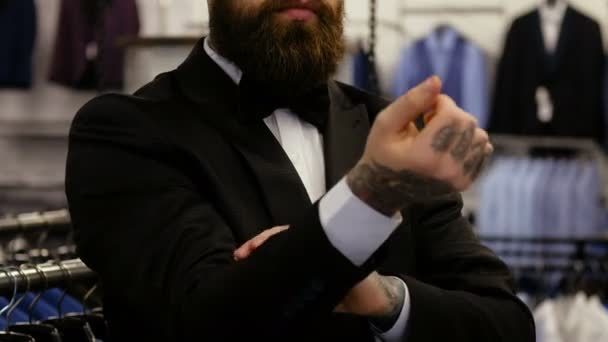 Weergave van een elegant gekleed bebaarde man sluit die proberen op een pak terwijl je in een kledingwinkel van de mens. - Video