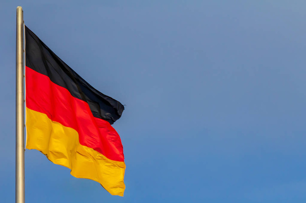 ドイツ連邦共和国、ドイツの国旗は青い空を背景に手を振る - 写真・画像