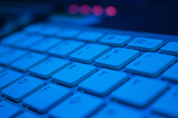 バック グラウンドで 4 led の青い光でコンピューターのキーボードのクローズ アップ - 写真・画像