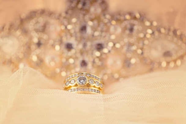Пасьянс діамант з трьома рядами дрібних діамантів в дизайні кластерного кільця в золоті з блискучим фоном і м'яким кремовим накладанням
 - Фото, зображення