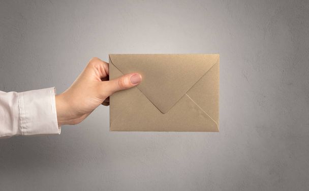 Hand holding envelope with empty wall background - Zdjęcie, obraz