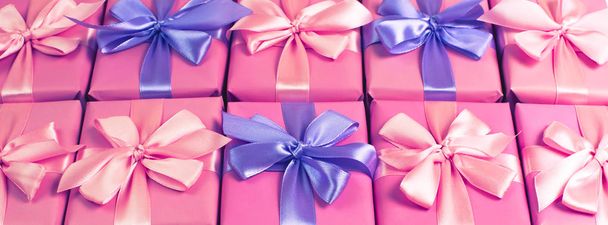 Banner Filas de cajas con regalos decoración cinta raso arco rosa. Una vista superior de la tonificación plana laico
 - Foto, imagen