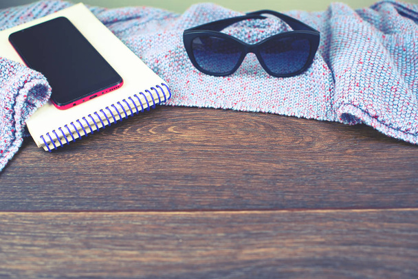 Lege ruimte op uw bureaublad mobiele telefoon gadget Kladblok zonnebril oude natuurlijke houten shabby achtergrond gebreid deken geruite paarse kleur toning - Foto, afbeelding