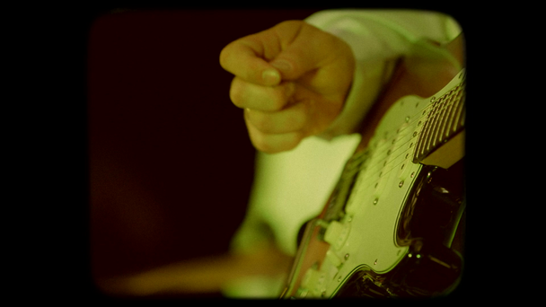 エレク トリック ギターの弦に手が触れます。レトロなスタイルの 8 mm フィルム. - 映像、動画
