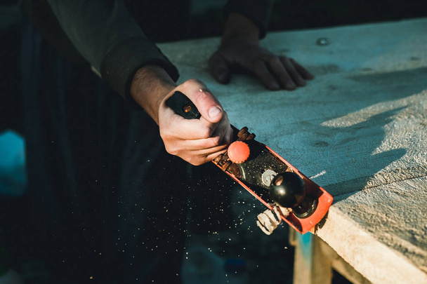 Man woodworker carpenter working with a hand plane. Planing a board is flying shavings. Master manual labor. - Foto, imagen