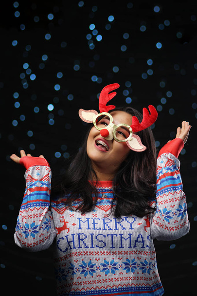Asian Girl Wearing Christmas Sweater and Christmas Reindeer Glasses Red Nose. Enjoy Glowing Snow - Photo, Image