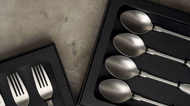 Top view of silver collection of forks and spoons in black boxes on grey concrete background - Valokuva, kuva