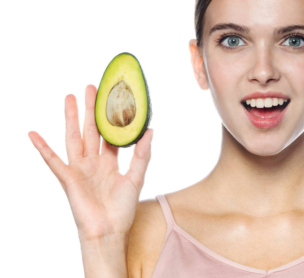 portrait of attractive young caucasian smiling cheerful woman isolated on white studio shot eating avocado looking at camera toothy smile - Φωτογραφία, εικόνα