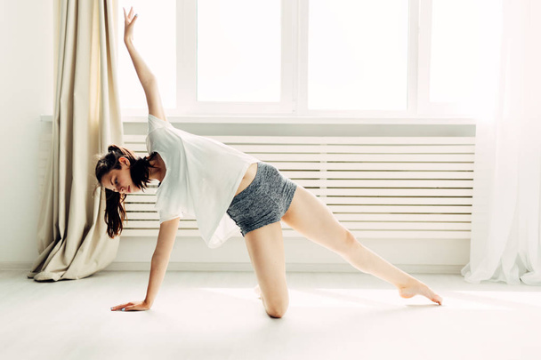 Young beautiful girl doing warm-up contemporary at home - Photo, Image