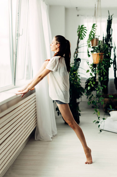 Young beautiful girl doing warm-up contemporary at home - Foto, Imagen