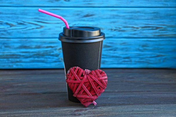 černá papírového kelímku s kávou a červené srdce na stole poblíž modré zdi - Fotografie, Obrázek