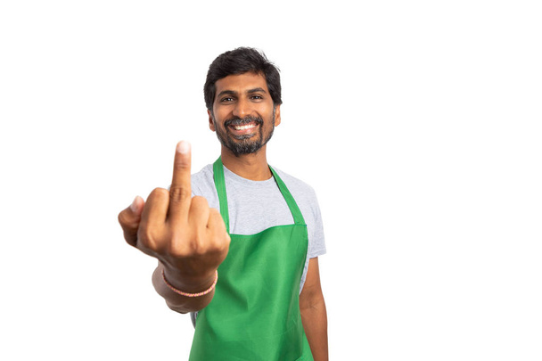 ホワイト スタジオの背景に分離された皮肉な笑顔で中指を保持しているインドのスーパー マーケットやハイパー マーケットの男性社員 - 写真・画像