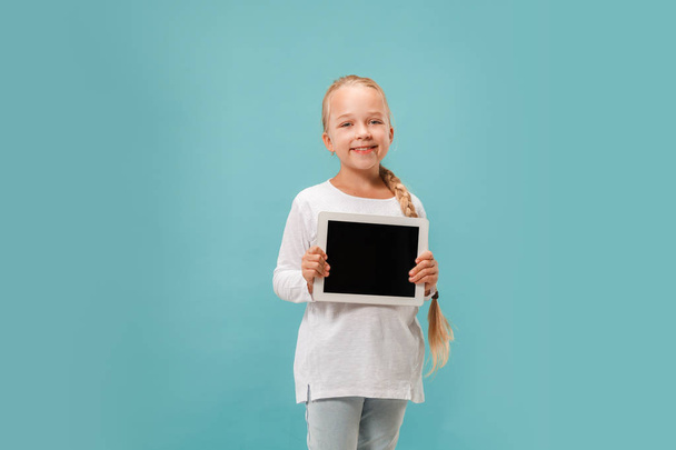 Little funny girl with tablet on blue background - Foto, imagen