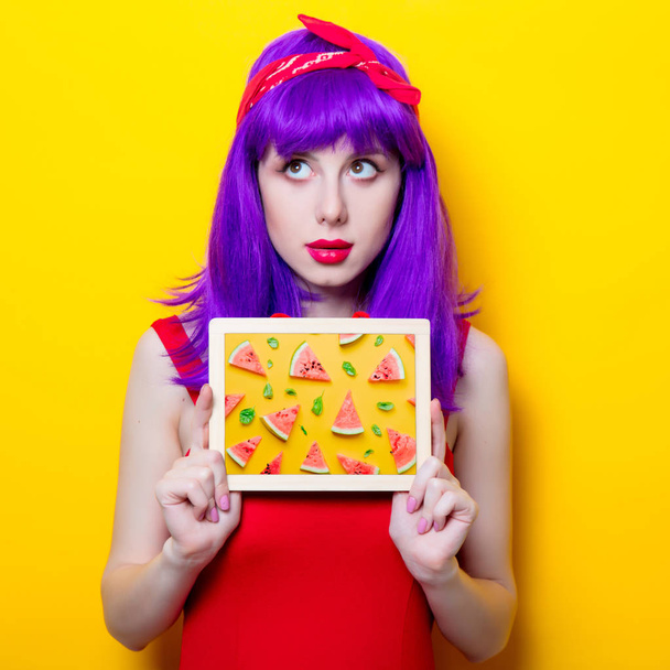 Portret młodej dziewczyny zaskoczony z fioletowy kolor włosów i tablica na żółtym tle - Zdjęcie, obraz