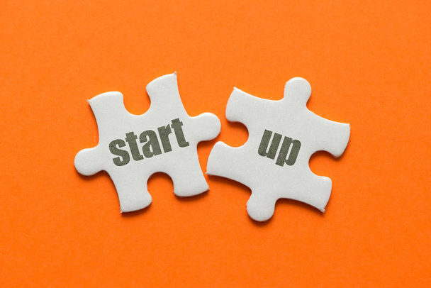 A palavra start-up em dois quebra-cabeça de correspondência no fundo laranja
. - Foto, Imagem