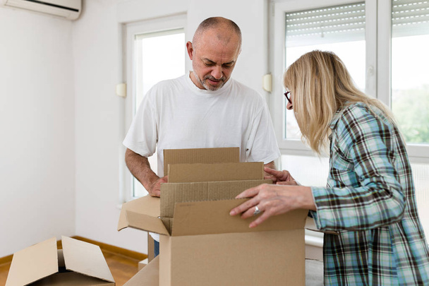 Happy middle aged couple with boxes moving into new home or apartment. Real estate theme. - Valokuva, kuva