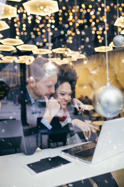 Multi raciale Business man en vrouw samen te werken in een modern café of restaurant. Uitzicht vanaf straat door raam glas. - Foto, afbeelding