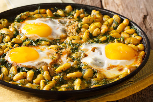 Иранский Багали Гатог рагу из бобов и укропа с жареными яйцами, чесноком и куркумой крупным планом в сковороде на столе. hhhonta
 - Фото, изображение