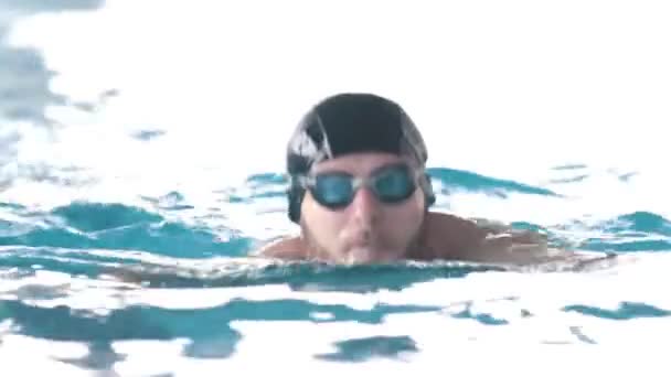 Vammainen mies ui uima-altaassa kameraa kohti
 - Materiaali, video