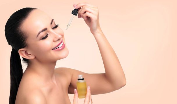 Detailní záběr kosmetické oleje na obličej mladé ženy s pipetou. Kosmetické terapie koncept. - Fotografie, Obrázek