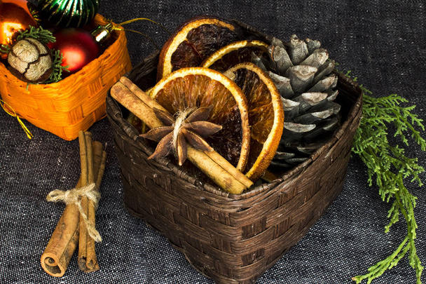 Arance secche, bastoncini di cannella, stelle di anice, coni e decorazioni natalizie nei cestini marrone e arancione
 - Foto, immagini