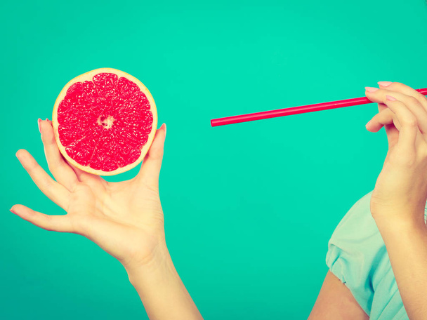 Healthy diet, refreshing food full of vitamins. Woman drinking juice from juicy fruit, red grapefruit - Фото, изображение