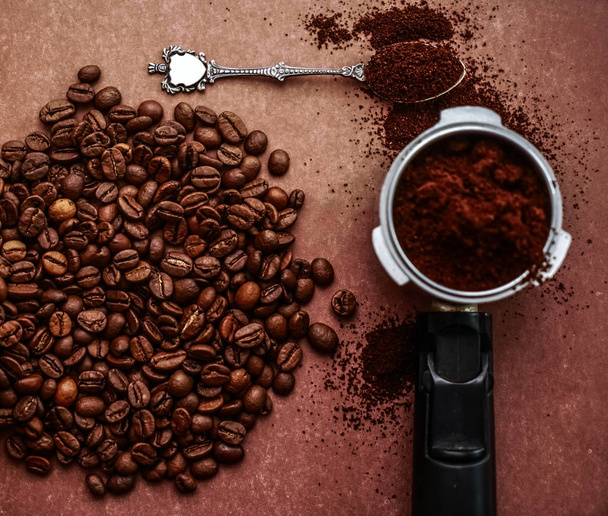 Black coffee beans in cafe on dark brown textured background. coffee machine. top view. full spoon - Foto, immagini