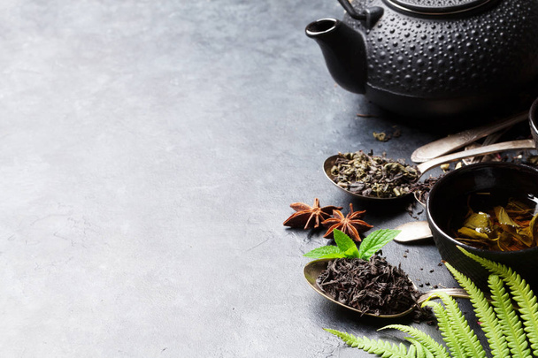 Erilaisia teetä ja teekannu kulhoja tumma kivi tausta kopioi tilaa
 - Valokuva, kuva