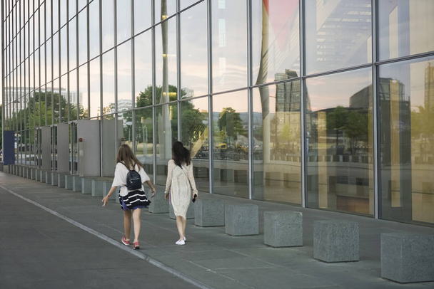 photo of two young women, walking  on road in city.   modern city.    - Fotoğraf, Görsel